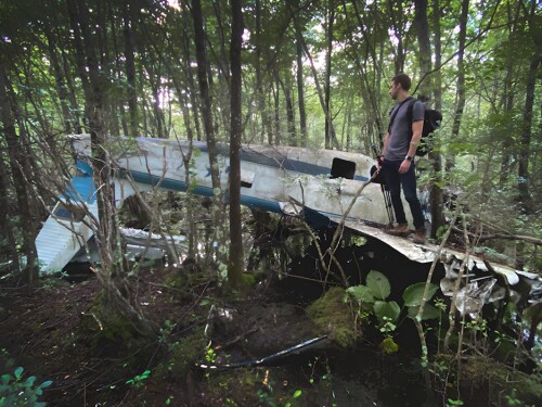 Jason Allard views an abandoned plane in the woods.